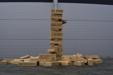 Klasszikus építkező társasjáték óriás kivitelben. A Jenga társasjáték lényege, hogy a fahasábokból álló toronyra újabb és újabb szinteket építs úgy, hogy az alulról kihúzott hasábokat egyre feljebb helyezed! Feszült figyelem és végtelen nyugalom szükséges, mert ha kicsit is megremeg a kezed, összedől az építmény. A győztes minden esetben az lesz, aki az utolsó hasábot sikeresen feltette a torony tetejére mielőtt az leborulna.
Ajánlott korosztály: 6-99 éves korig.